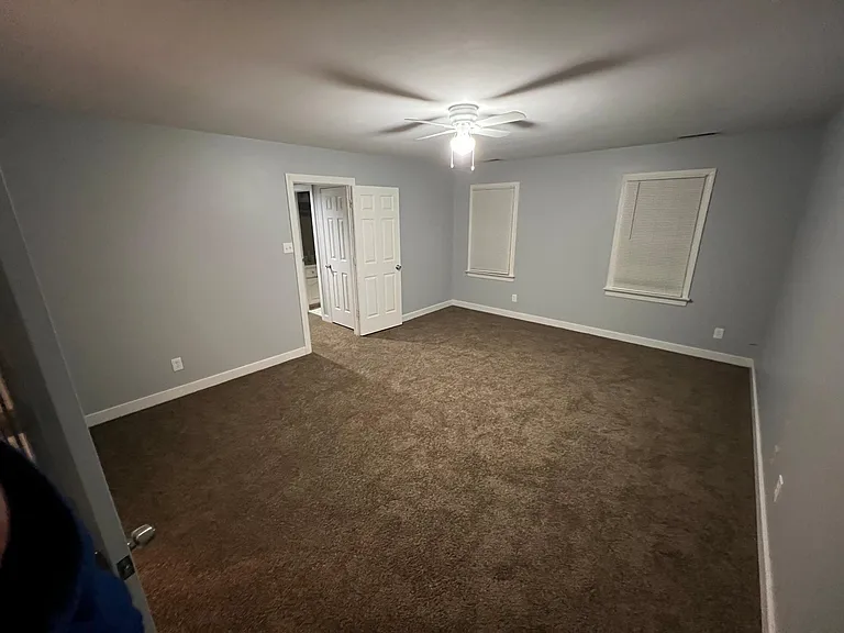 Photo of master bedroom, straight ahead is the door to the hallway, door pictured to the left is the door to the master bathroom with walk in closet. Windows face the front of the home