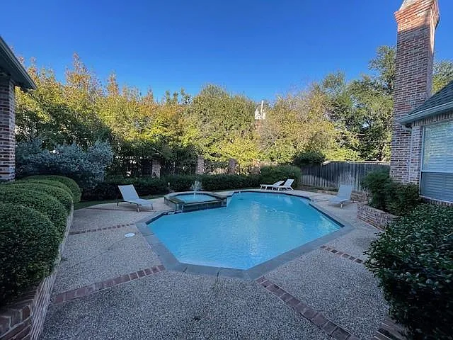 View of pool featuring a patio area, a pool with connected hot tub, and a fenced backyard