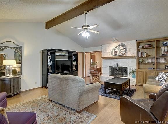 A very large great room with built in bookcases. cathedral ceiling, beams and rock fireplace