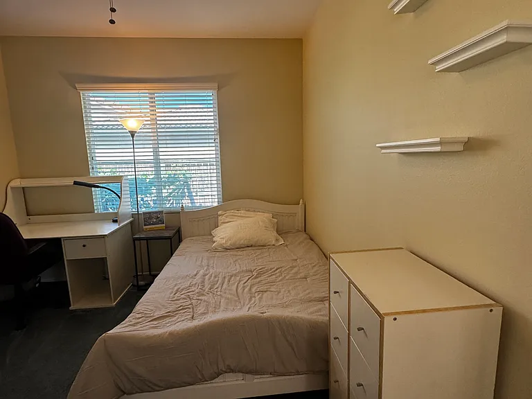 Bedroom#2: bed, basic bedding, ceiling light/fan, desk, desk chair, wall shelves, chest of drawers, floor lamp, large window with blinds & side yard view