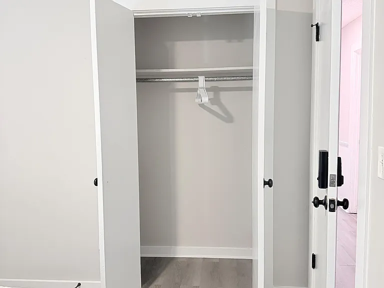 Bedroom closet with double doors offers a hanging rod and upper shelf, providing convenient in-room storage.