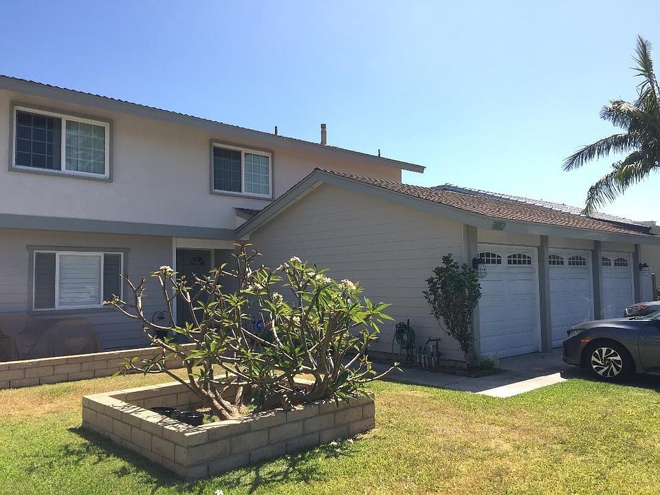 3 car garage with beautiful front patio and plumeria and hibiscus plants.