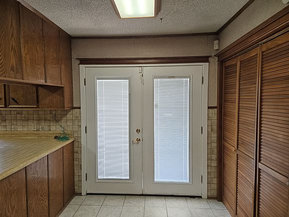 French doors in kitchen leading to patio, with washer and dryer hookups behind louver doors