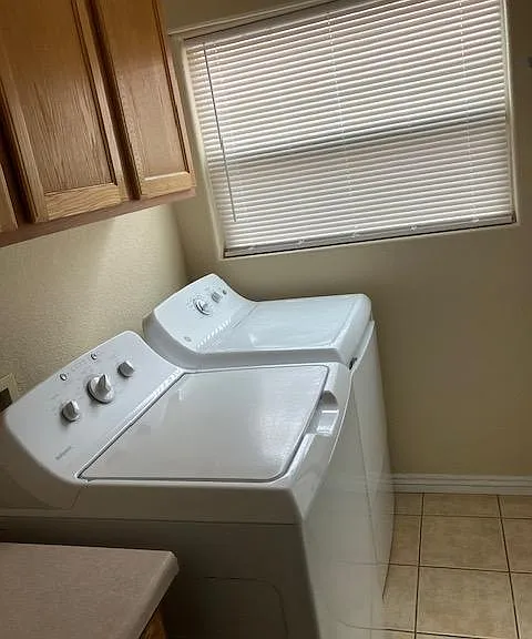 Dedicated laundry area with side-by-side washer and dryer, plus upper cabinetry for convenient storage.