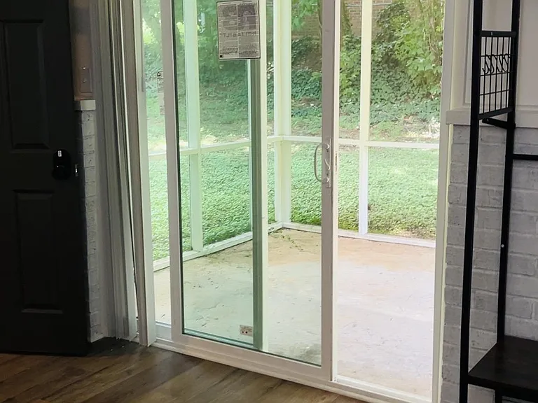 Bedroom with sliding glass doors opening to a screened patio, plus durable flooring and space for storage or a desk.