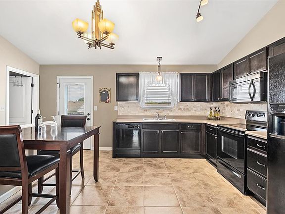 Open eat in Kitchen has upgraded lighting, vaulted ceiling and backsplash.  Door leads to low maintenance deck with stairs leading to large, level back yard.