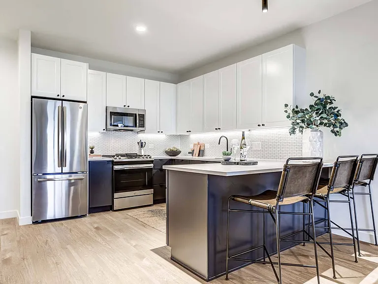 Cook, dine, and entertain in a modern kitchen with stainless steel appliances, including a refrigerator, microwave, and oven, plus bar stools for a comfortable, interactive space.