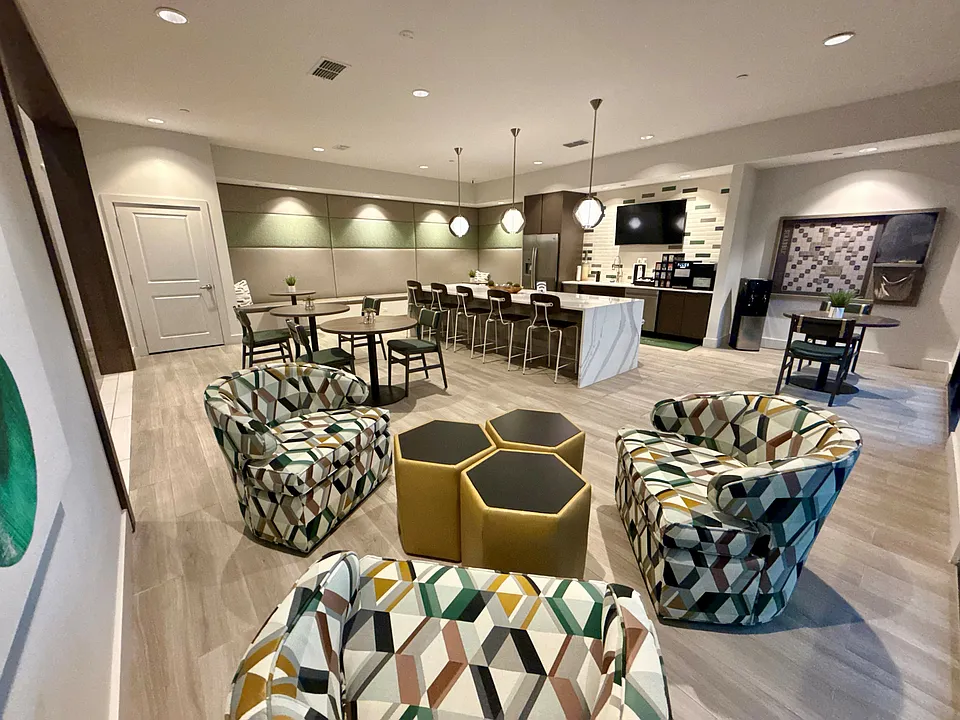 Integra Palms offers a stylish communal lounge featuring modern geometric chairs, cozy lighting, and a sleek kitchen area.