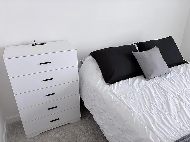 Furnished bedroom featuring a neatly made bed and a dresser for convenient in-room storage.