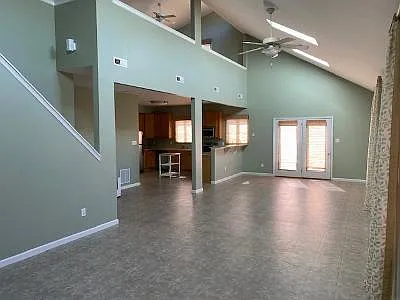 View one of downstairs. Very open. Stairs to upstairs loft. Door to patio. View of kitchen.