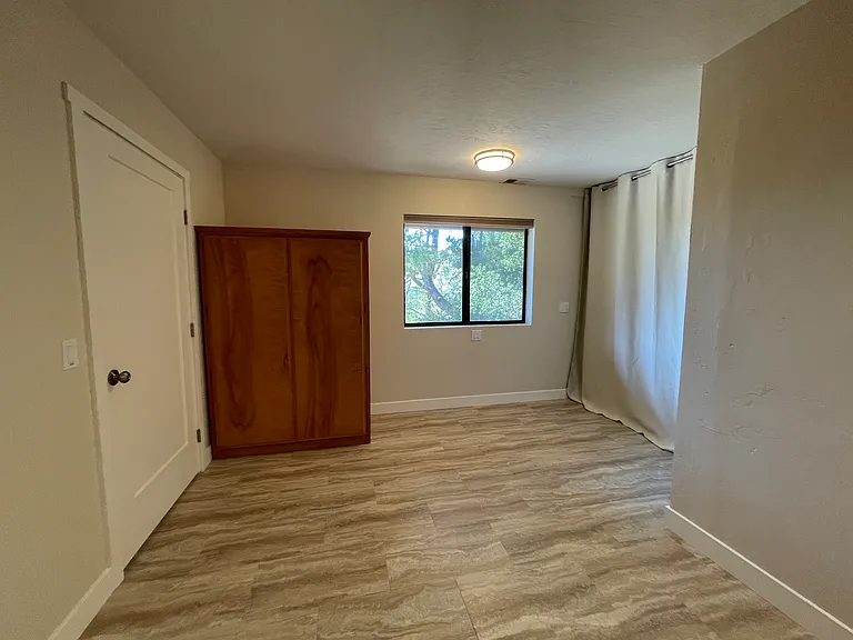 Bedroom looking out toward window and laundry curtain. Bath is to the right.