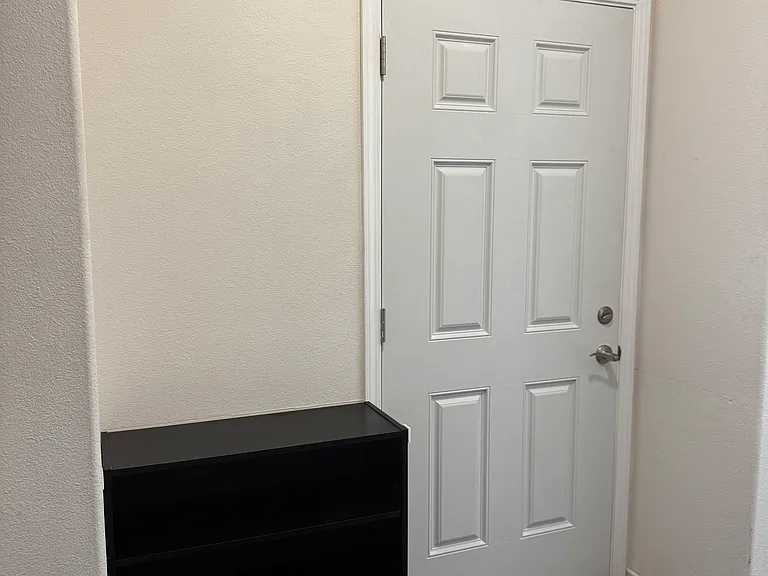 Interior view of private entry/exit door of house for three rental bedroom residents ; shoe rack next to private entry/exit door.