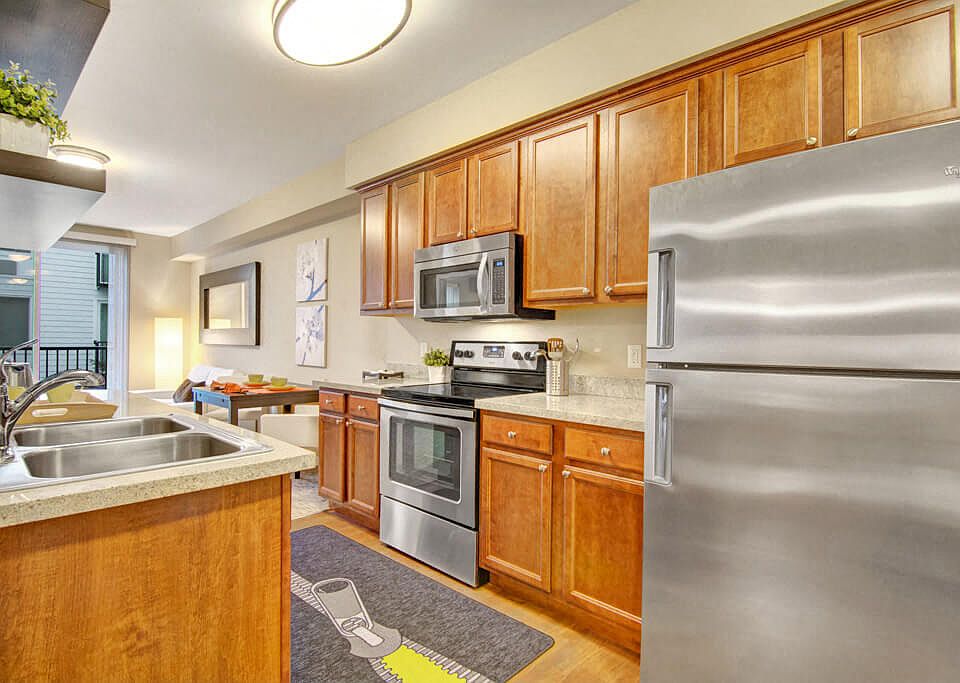 An open kitchen with stainless steel appliances and shelving with a view through to the living area