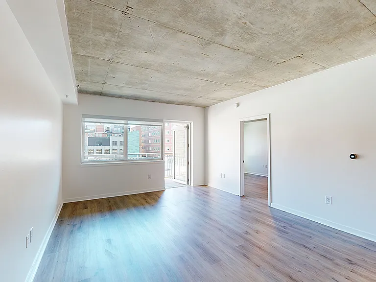 Apartment living room with wood-style flooring and a balcony/patio in select homes.