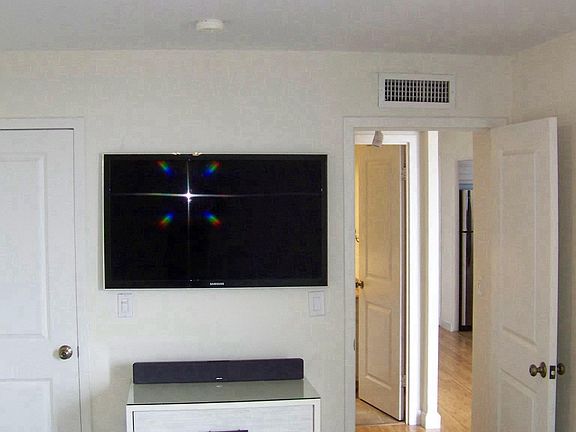 Carpeted bedroom with walk-in closet and wall-mounted TV