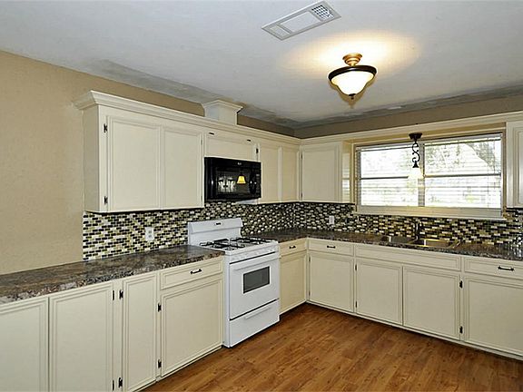 Amazing kitchen. Glass backsplash, custom cabinets, crown molding and vinyl floor. The contractor was finishing up as this photo was taken. A few more touch ups so you won't need to do a thing.