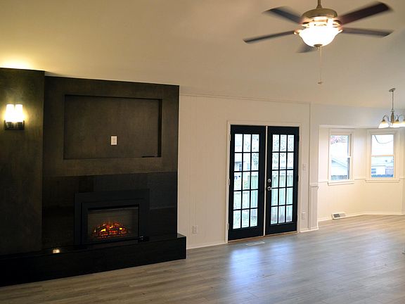 Living Room looking towards fireplace w/ TV hookups above, door to rear yard and bay window eat-in area.