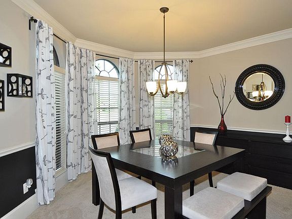 Formal dining area w/ crown moulding, chair rail, custom drapes, & wine rack