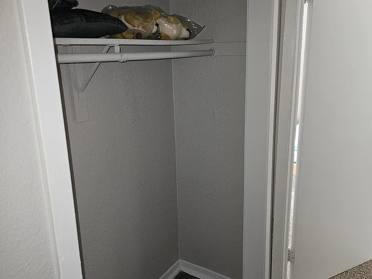 Dedicated closet space with a hanging rod and upper shelf for easy clothing and linen storage.