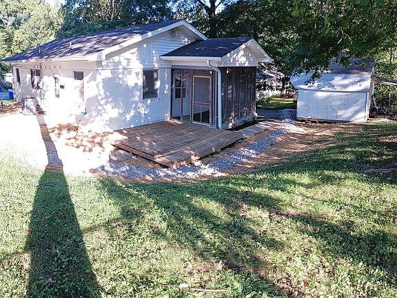 Outdoor living space with screened in porch and large deck in shady back yard.