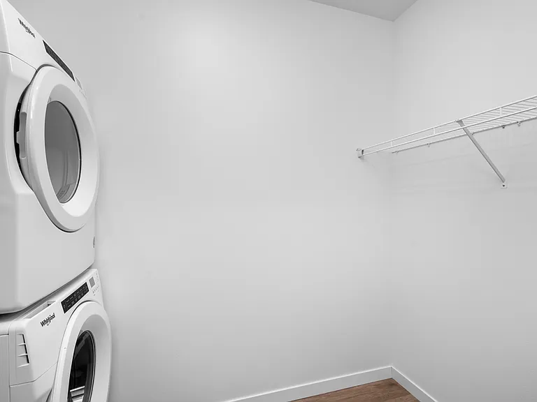 Sleek laundry room with modern stackable washer and dryer, featuring clean white walls and a convenient storage shelf. Sleek laundry room with modern stackable washer and dryer, featuring clean white walls and a convenient storage shelf.