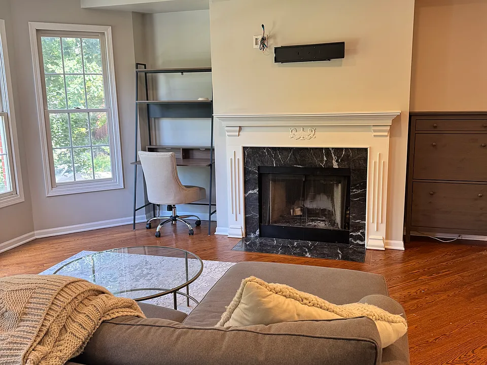 Bright, open living area featuring bay windows, hardwood floors, and a marble gas fireplace. Light-filled bay window alcove with a dedicated work-from-home desk nook.