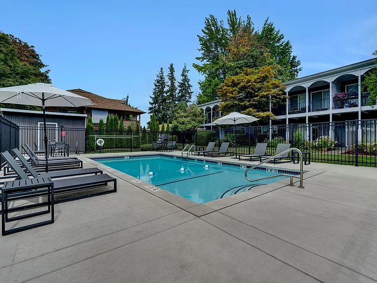 a swimming pool with lounge chairs and umbrellas in front of a building Sunset Station Apartments Portland Oregon
