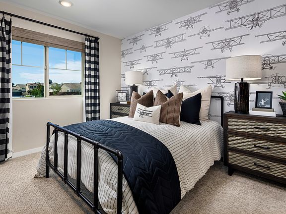 A cozy and stylish bedroom with a patterned accent wall, a metal bed frame, and a mix of neutral and