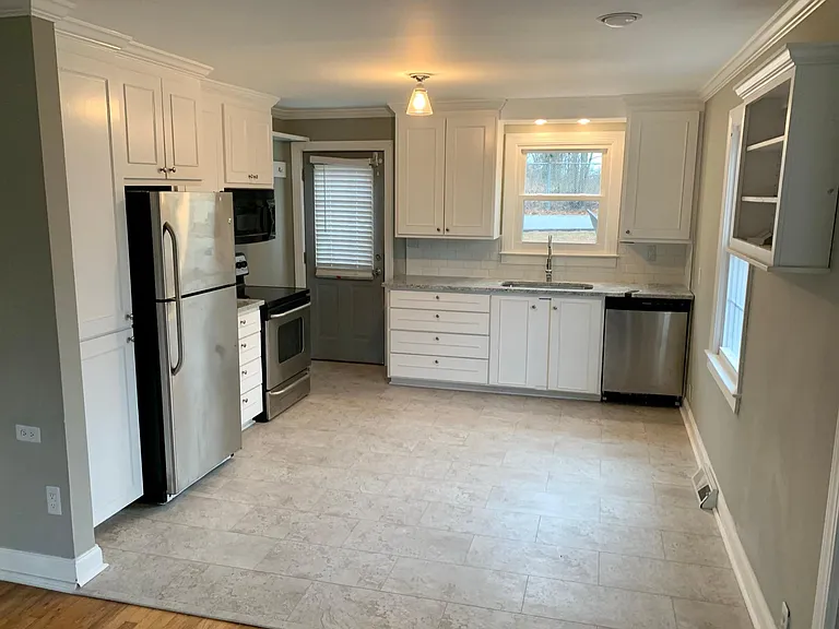 Updated kitchen with farmhouse sink and stainless steel appliances.