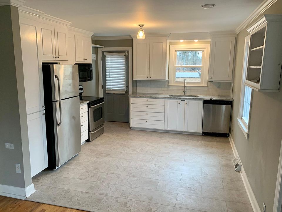 Updated kitchen with farmhouse sink and stainless steel appliances.