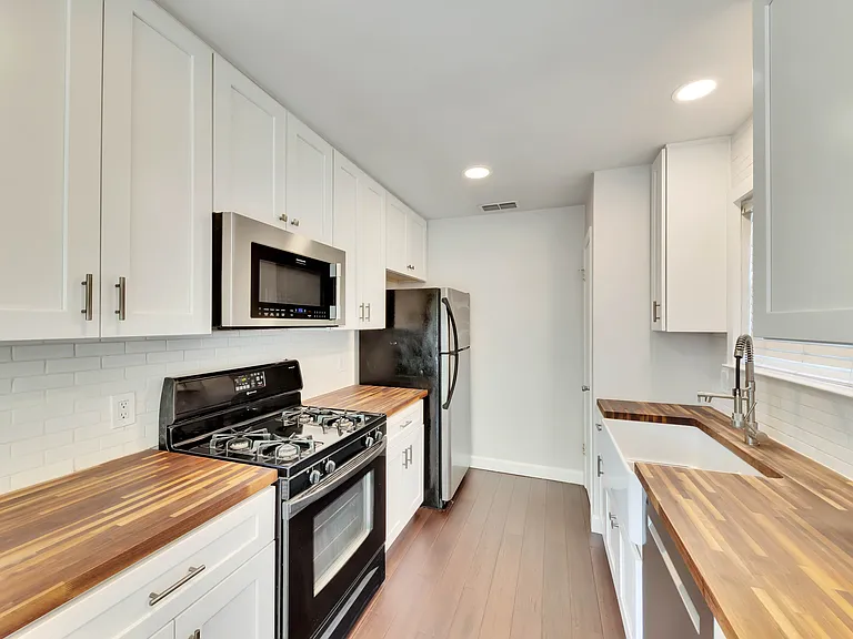 Modern Kitchen: featuring beautiful butcher block countertops, crisp white shaker style cabinets, and sleek stainless steel appliances.