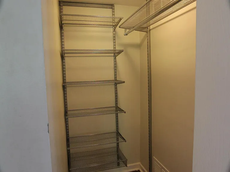 Walk in bedroom closet with shelving system.