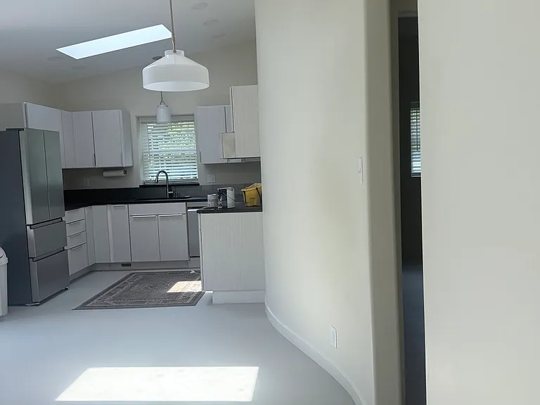 Curved wall in the foreground with doorway leading to bedroom, bathroom, and utility closet.
We envisioned a round banquette table with a couple of chairs under the hanging light.
