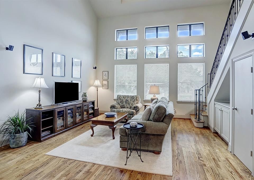 The spacious living room has high ceilings, richly toned wooden floors and an abundance of natural light. There are built-in cabinets and a storage closet under the stairs.