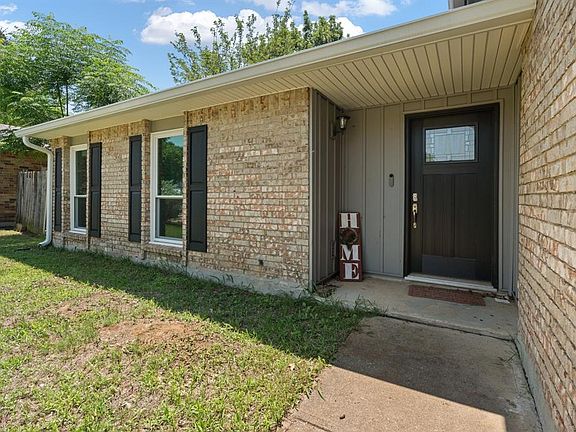 Doorway to property featuring brick siding and a lawn