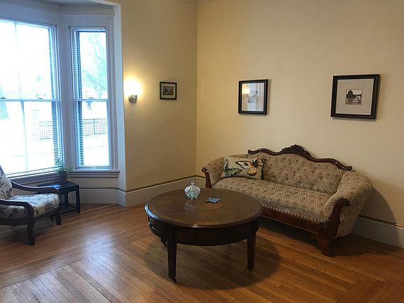 Large living room with period furniture. The bay window looks out onto a park. The living room gets plenty of natural light.