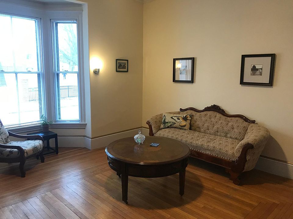 Large living room with period furniture. The bay window looks out onto a park. The living room gets plenty of natural light.