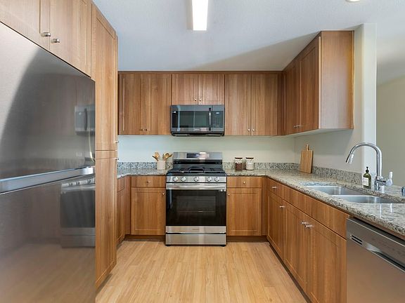 Updated Finishes kitchen with oak cabinetry, beige speckled granite countertops, stainless steel appliances, and hard surface flooring