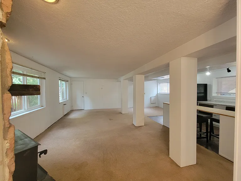 Downstairs living area with room for two couches, chairs, TV wall space, and more. New carpet coming soon!