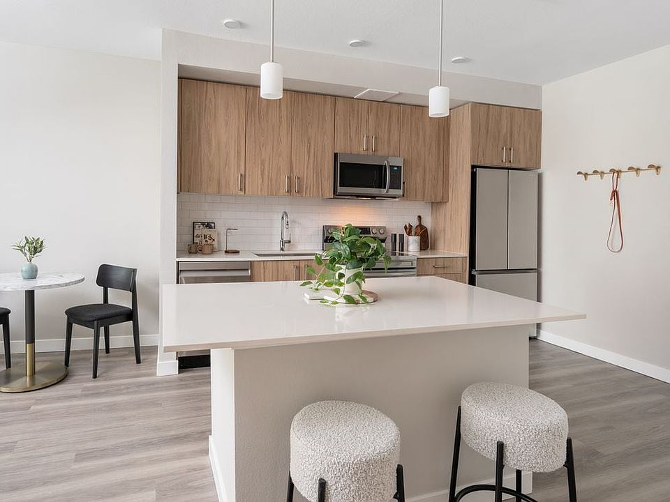 Finish Package II Kitchen with oak cabinetry, white quartz countertops, white tile backsplash, stainless steel appliances, pendant lighting, and hard-surface vinyl plank flooring