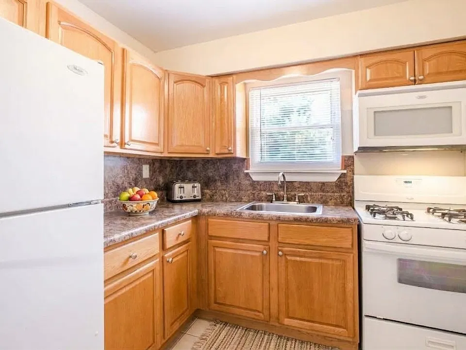 Warm wood cabinetry, granite countertops, and stainless steel appliances bring style and function to this Woodmere Apartments kitchen. Explore available homes and schedule a tour today.