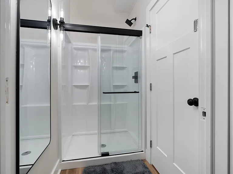 Updated bathroom with a glass-enclosed shower, built-in shelving, and matte-black fixtures for easy daily use.
