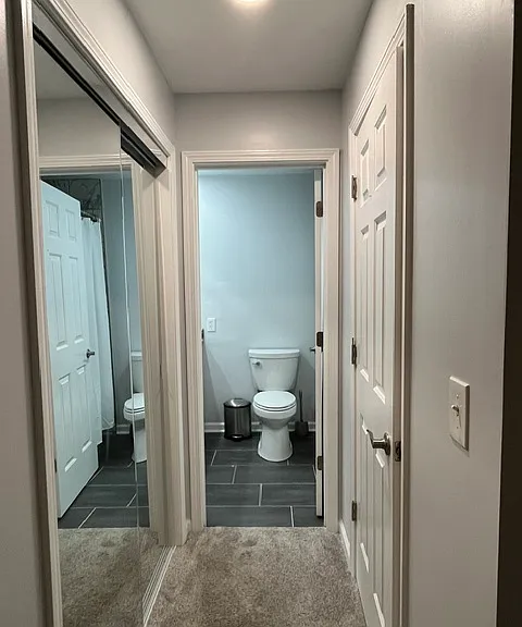 View from bedroom into bathroom. Mirrored sliding door closet on the left and walk in closet to the right.