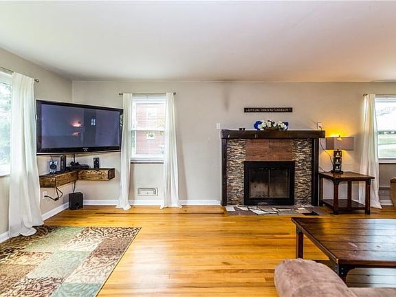 Spacious with a lot of natural light this living room features hardwood flooring and a wood burning fireplace.