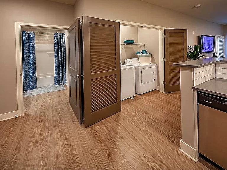 Designed for daily ease: This smart apartment layout reveals a full-size washer and dryer tucked behind sleek doors for a seamless look.