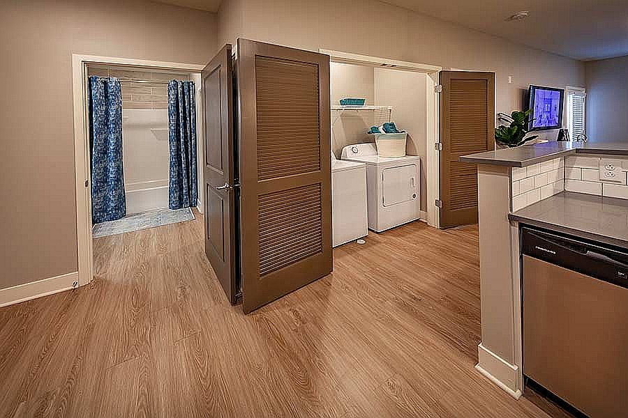Designed for daily ease: This smart apartment layout reveals a full-size washer and dryer tucked behind sleek doors for a seamless look.