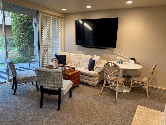Seating area with big screen TV and patio to left.