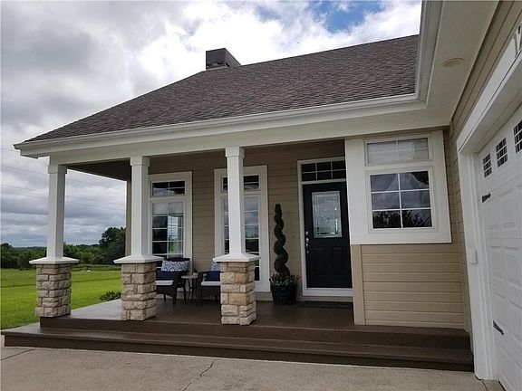 Covered front porch features stained concrete and updated stone pillars.  You'll pass some pleasureable hours here!