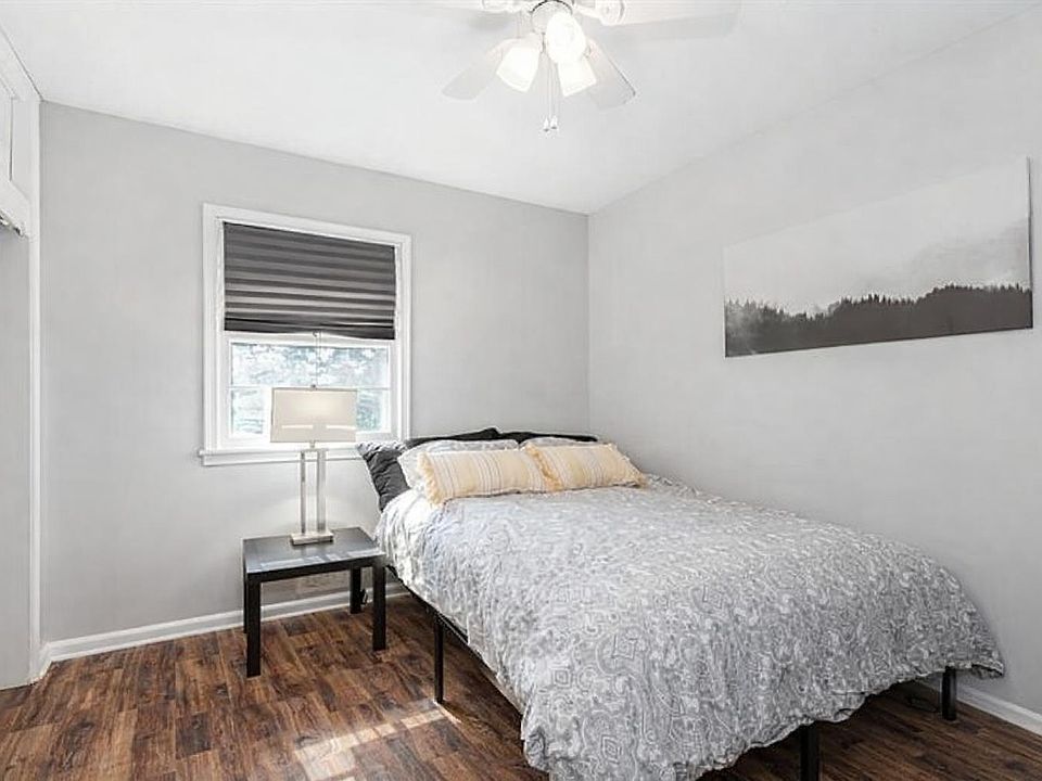 Well-appointed bedroom with a comfortable bed, nightstand, ceiling fan, and a window with blinds for light control.