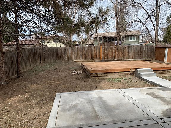 Fenced in backyard with concrete patio and lounging deck.